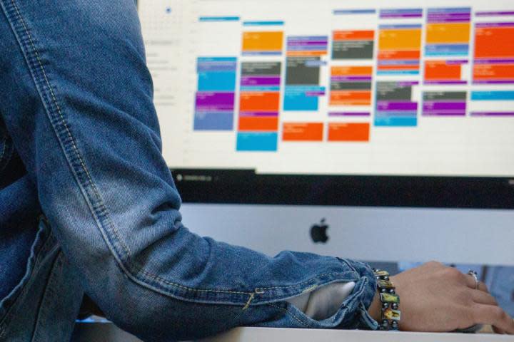 A person using a calendar app on an Apple iMac.