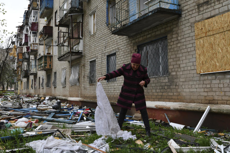 A woman looks for goods dropped from the apartment building partly damaged by shelling, in Kramatorsk, Ukraine, Thursday, April 14, 2022. (AP Photo/Andriy Andriyenko)