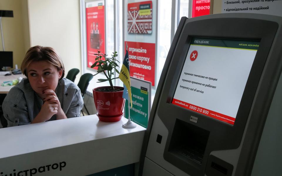 An employee sits next to a payment terminal out of order in Ukraine