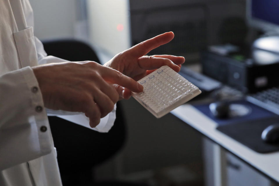 Vincent Enouf, Deputy director of National Flu Center displays samples prior to put them into machine for analyze at Pasteur Institute in Paris, Thursday, Feb. 6, 2020. Scientists at the Pasteur Institute developed and shared a quick test for the new virus that is spreading worldwide, and are using genetic information about the coronavirus to develop a potential vaccine and treatments. (AP Photo/Francois Mori)