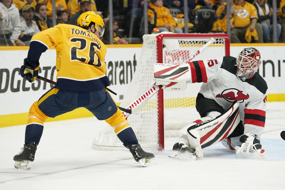 New Jersey Devils goaltender Jonathan Bernier (45) deflects a shot by Nashville Predators center Philip Tomasino (26) in the second period of an NHL hockey game Friday, Nov. 26, 2021, in Nashville, Tenn. (AP Photo/Mark Humphrey)