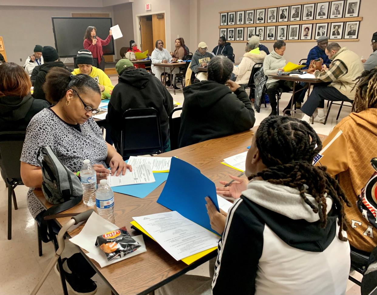 Tiffany Taylor, left, a tenant at Victory Square Apartments in Canton for eight years, completes paperwork Tuesday during a meeting with relocation officials on how the tenants can get help with finding a new home.