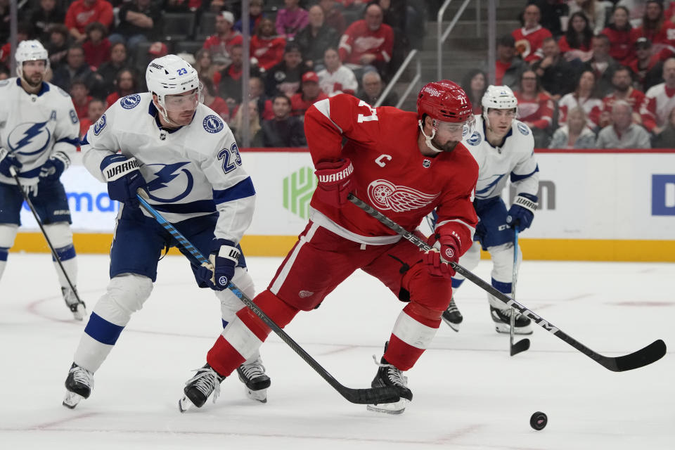 Detroit Red Wings center Dylan Larkin (71) controls the puck next to Tampa Bay Lightning center Michael Eyssimont (23) during the second period of an NHL hockey game, Saturday, Oct. 14, 2023, in Detroit. (AP Photo/Carlos Osorio)
