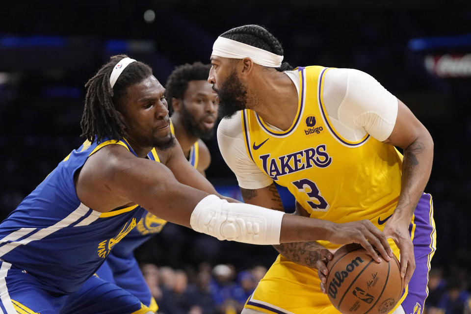 Golden State Warriors forward Kevon Looney, left, reaches in on Los Angeles Lakers forward Anthony Davis during the first half of an NBA preseason basketball game Friday, Oct. 13, 2023, in Los Angeles. (AP Photo/Mark J. Terrill)