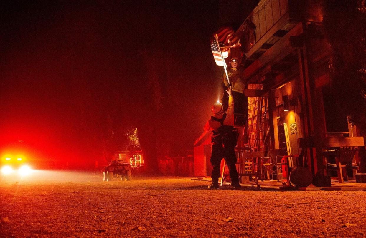 Firefighters remove a flag from a property as flames race into the area during the Kincade fire in Healdsburg, Calif. on Oct. 27, 2019.