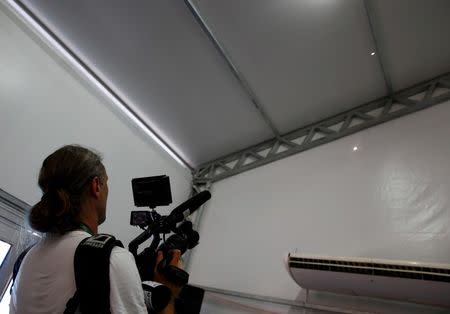 A television cameraman films two holes in the tent that serves as a media center for the Deodoro Olympic Equestrian Center during the first day of competition of the Rio 2016 Olympic Games, in Rio de Janeiro, Brazil, August 6, 2016. REUTERS/Tony Gentile