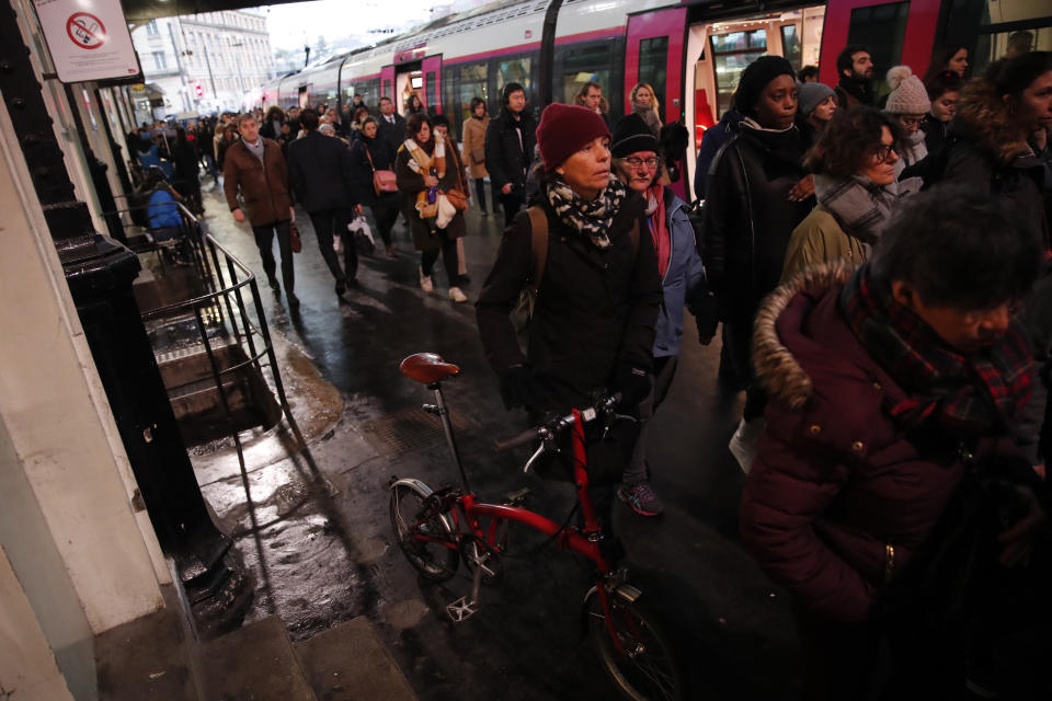 Commuters walk to get on a train at the Gare Saint Lazare station in Paris, France, Monday, Dec. 16, 2019. French transport strikes against a planned overhaul of the pension system entered their twelfth day Monday as French president Emmanuel Macron's government remains determined to push ahead with its plans. (AP Photo/Francois Mori)