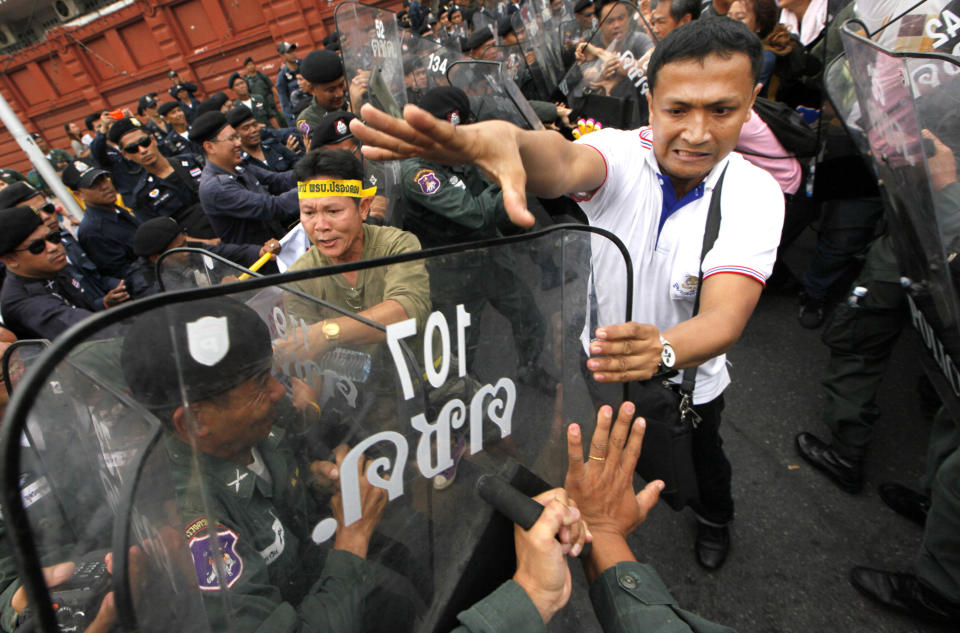 A member of the People's Alliance for Democracy (PAD), right, scuffles with police officers on a street corner leading to parliament house Friday, June 1, 2012. Thai politics has shifted its focus to the streets again after thousands of protesters have deterred lawmakers from deliberating a bill they claimed could whitewash the wrongdoing of politicians and bring back ousted premier Thaksin Shinawatra. (AP Photo/Wason Wanichakorn)