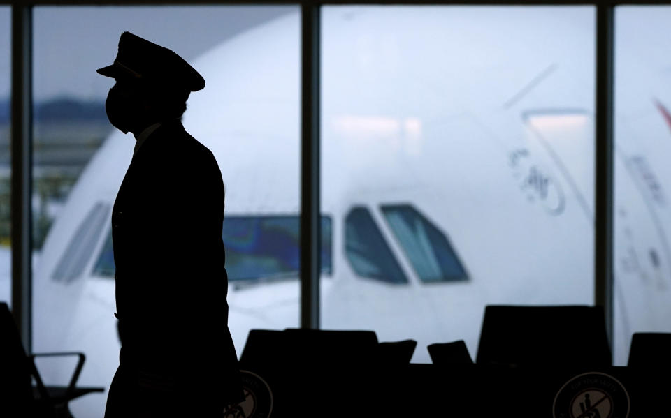 FILE - In this Thursday, Feb. 18, 2021, file photo, a pilot wears a face mask to help prevent the spread of the coronavirus as he walks through a terminal at Hartsfield-Jackson International Airport in Atlanta. On Friday, Oct. 22, The Associated Press reported on stories circulating online incorrectly claiming that vaccine-related strokes in pilots have caused an “epidemic of plane crashes.” (AP Photo/Charlie Riedel, File)