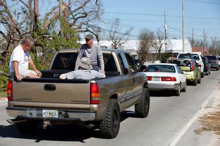 James Beardon sits with two of his neighbours while waiting to pick up food and water from a public distribution location in Parker, Florida, U.S., October 13, 2018. REUTERS/Terray Sylvester