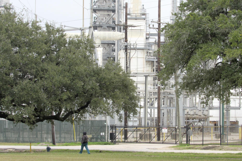 In this Thursday, Jan. 30, 2020, photo, Houston resident Guadalupe Ortiz takes her daily walk at a city park located across the street from her home and a Valero oil refinery. Houston's lack of zoning has resulted in residents like Ortiz living next to petrochemical facilities and businesses that handle hazardous substances. (AP Photo/ Juan Lozano)