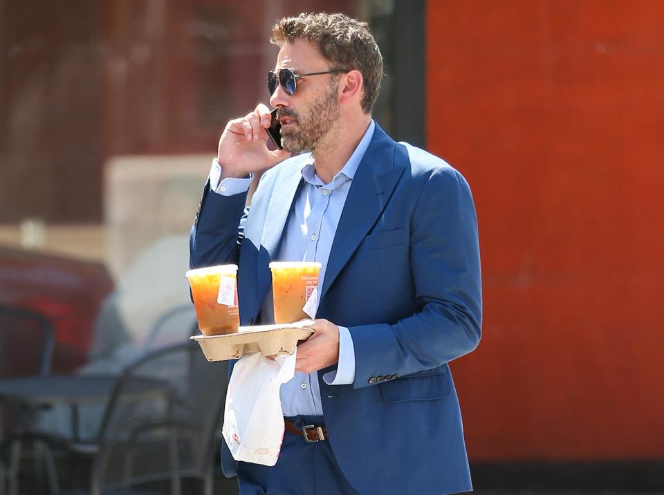 A closeup of Ben walking outside with coffee