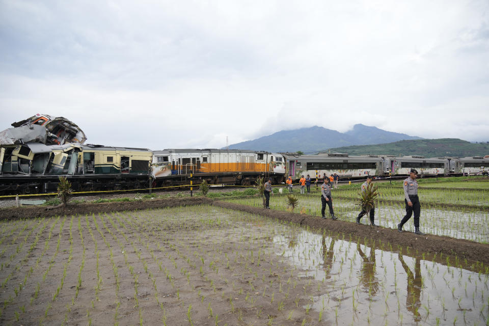 Inspectors walk near the wreckage after the collision between two trains in Cicalengka, West Java, Indonesia, Friday, Jan. 5, 2024. The trains collided on Indonesia's main island of Java on Friday, causing several carriages to buckle and overturn, officials said. (AP Photo/Achmad Ibrahim)