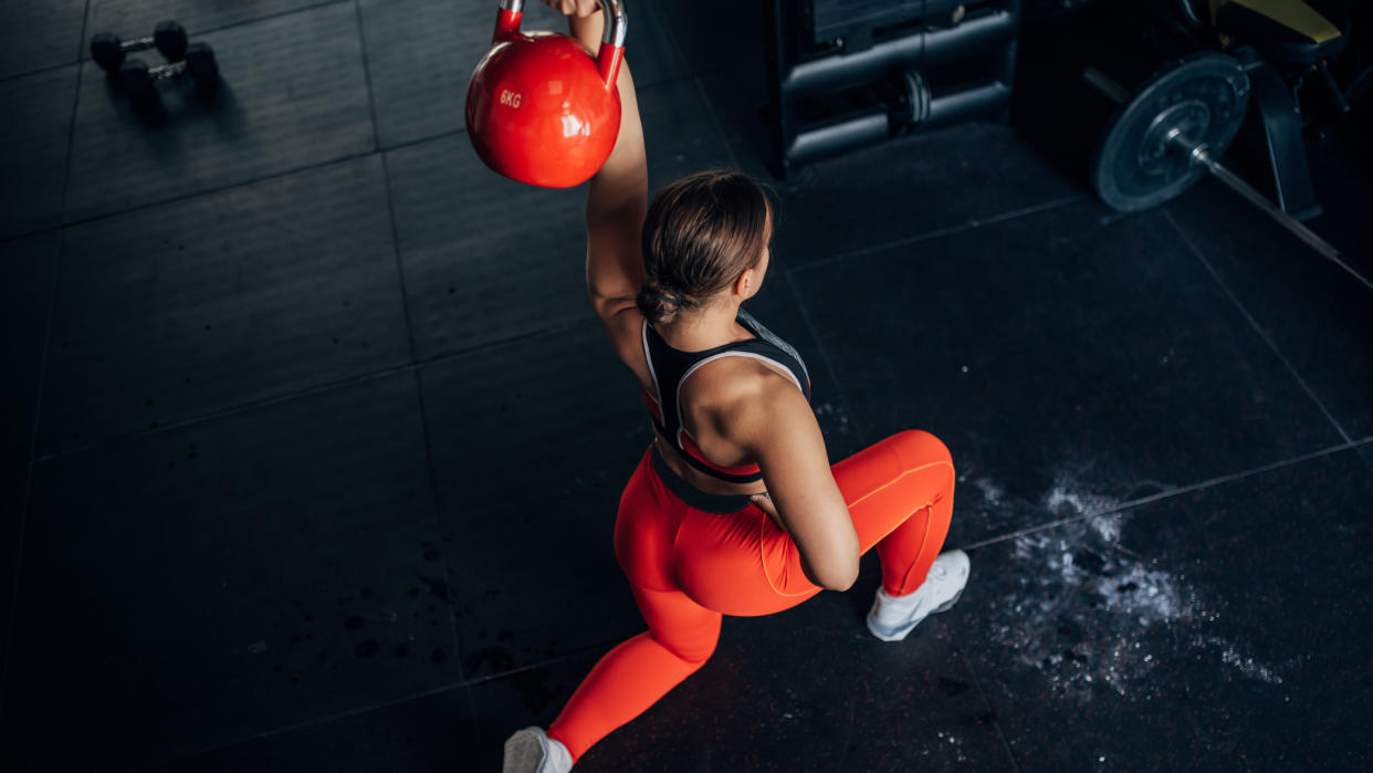  A photo of a woman performing a kneeling kettlebell press. 