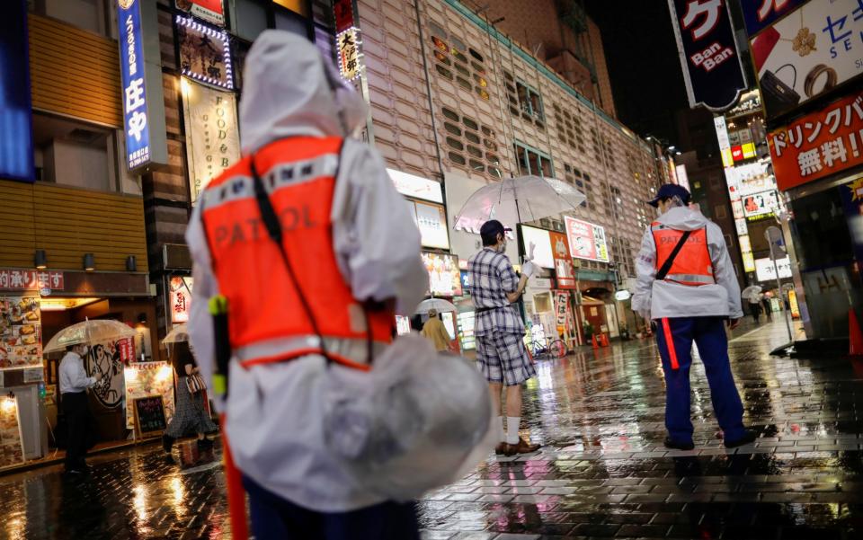 Security personnels of Toshima Ward conduct a reminder announcement to promote measures against the coronavirus on the street in Tokyo - REUTERS