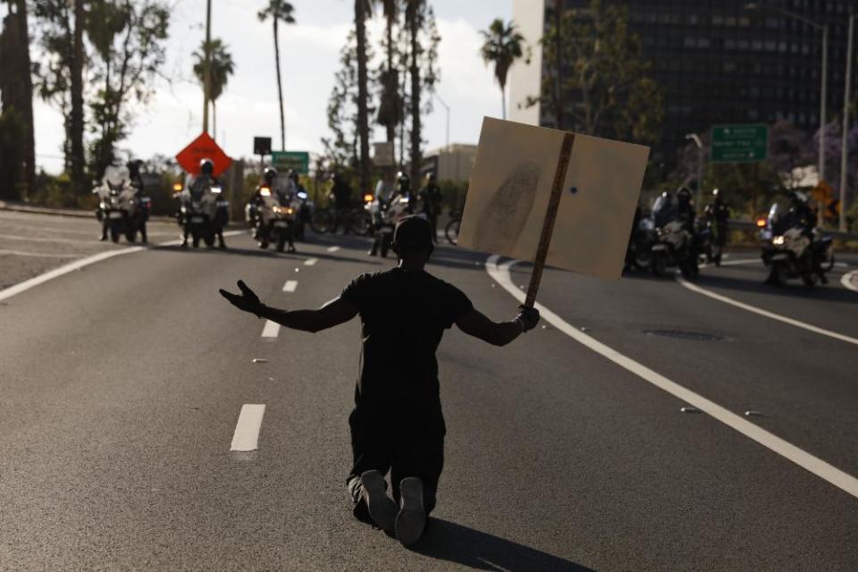 A man kneels on the street in front of police officers while chanting “I can’t breathe” in Los Angeles.