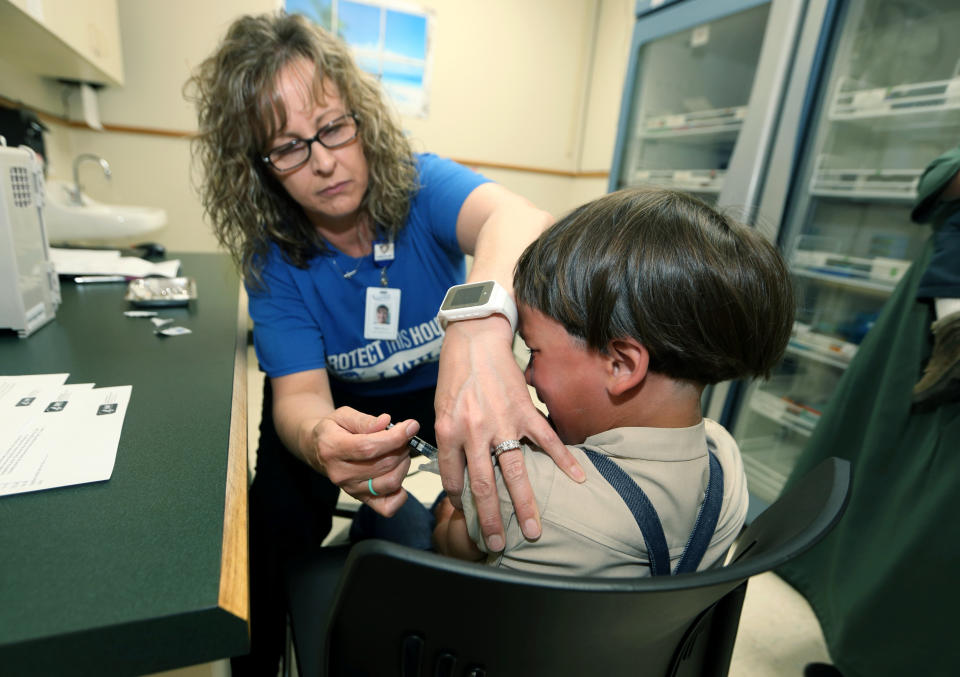 In this Friday, May 17, 2019 photo, Starr Roden, left, a registered nurse and immunization outreach coordinator with the Knox County Health Department, administers a vaccination to Jonathan Detweiler, 6, at the facility in Mount Vernon, Ohio. States are debating whether to make it more difficult for students to avoid vaccinations for religious or philosophical reasons amid the worst measles outbreak in decades, but children using such waivers are outnumbered in many states by those who give no excuse for lacking shots.Data reported to the Centers for Disease Control and Prevention shows a majority of unvaccinated or undervaccinated kindergartners in 10 of 27 states reporting were allowed to enroll in school without any exemption. (AP Photo/Paul Vernon)