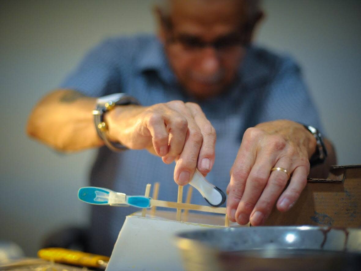 Roy Lafosse, a seniors' home resident in Corner Brook, keeps a steady hand while applying pieces to his latest cardboard boat. (Troy Turner/CBC - image credit)