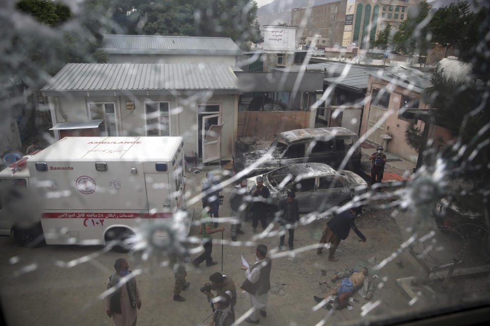 Afghan security security officers are seen through the shattered window of a maternity hospital after gunmen attacked, in Kabul, Afghanistan, Tuesday, May 12, 2020. Gunmen stormed the hospital in the western part of Kabul on Tuesday, setting off a shootout with the police and killing several people. (AP Photo/Rahmat Gul)
