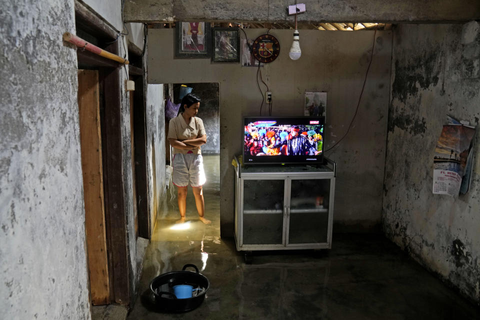 Dwi Ulfani stands inside her flooded home in Timbulsloko, Central Java, Indonesia, Saturday, July 30, 2022. When asking Ulfani what she wants to do after school— stay in the village or move elsewhere— she cries when responding in a whisper, "Move." (AP Photo/Dita Alangkara)