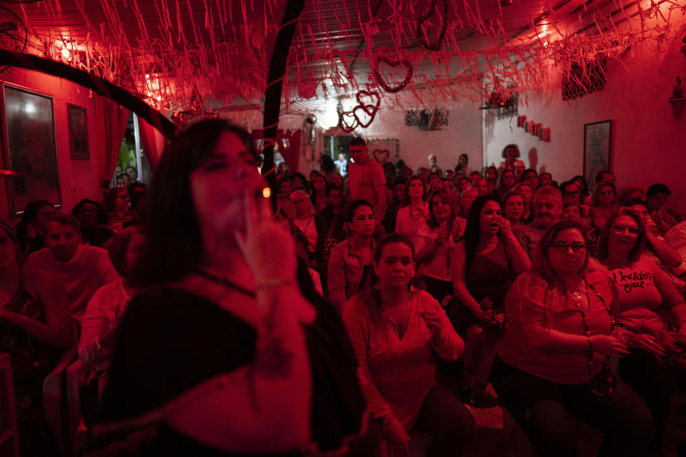 A devotee of Umbanda, a religion that was born in Brazil, smokes a cigarette during a gathering at the Umbanda Spiritual Center Casa de Caridade Santa Barbara e Iansa, in Rio de Janeiro, Brazil, Saturday, Sept. 3, 2022. (AP Photo/Rodrigo Abd)