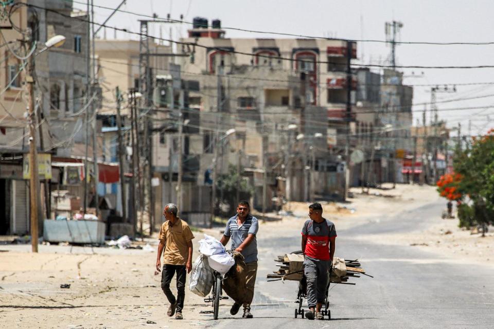 PHOTO: A man pulls a cart loaded with salvaged wood alongside another pushing a bicycle loaded with bags along a street in the eastern part of Rafah in the southern Gaza Strip on June 14, 2024. (Bashar Taleb/AFP via Getty Images)