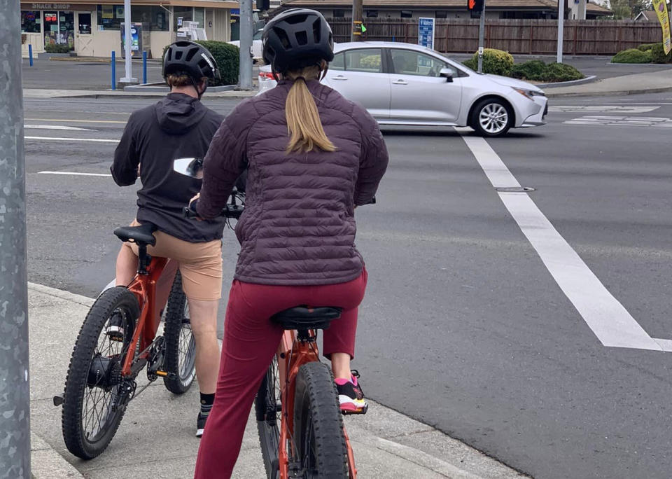 A picture of a boy and woman riding e-bikes on a US pavement.