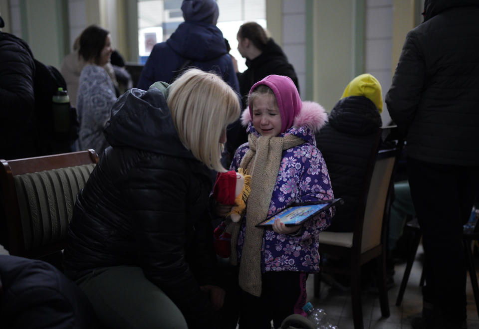 A woman speaks with a child as they wait in the train station, after fleeing Ukraine, in Przemysl, Poland, Tuesday, March 8, 2022. U.N. officials said Tuesday that the Russian onslaught has forced 2 million people to flee Ukraine. (AP Photo/Daniel Cole)