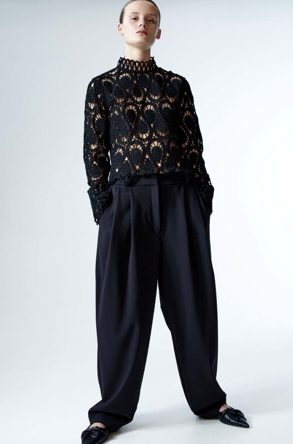 model wearing black wide-leg pants and black long-sleeve Crochet-Look Top (Photo via H&M)