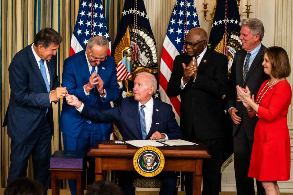 President Biden, seen handing a pen to Sen. Joe Manchin, with Sen. Chuck Schumer and Reps. James Clyburn, Frank Pallone and Kathy Castor at the White House.