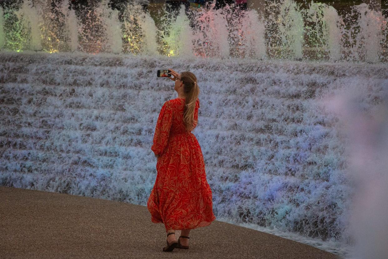 A woman takes a selfie while walking in the Watergarden during the city's reopening ceremony on Wednesday in Corpus Christi.