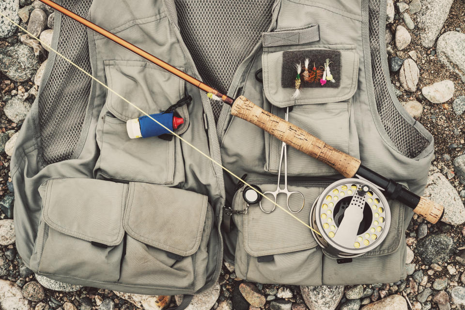 A salmon fisherman's vest and fly rod sitting on the river bank.
