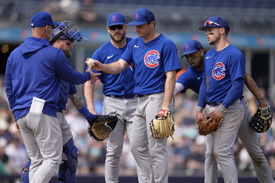 Chicago Cubs starting pitcher Hayden Wesneski, center, hands the ball to manager David Ross, left, during the third inning of a spring training baseball game against the Seattle Mariners, Monday, March 6, 2023, in Peoria, Ariz. (AP Photo/Abbie Parr)