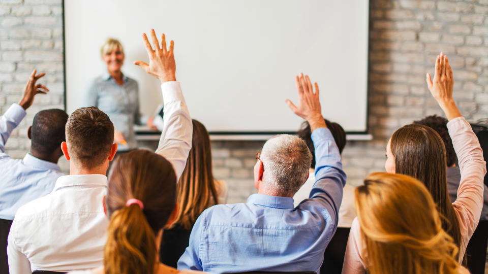 group of business people at a lecture raising their hand ready to answer the question