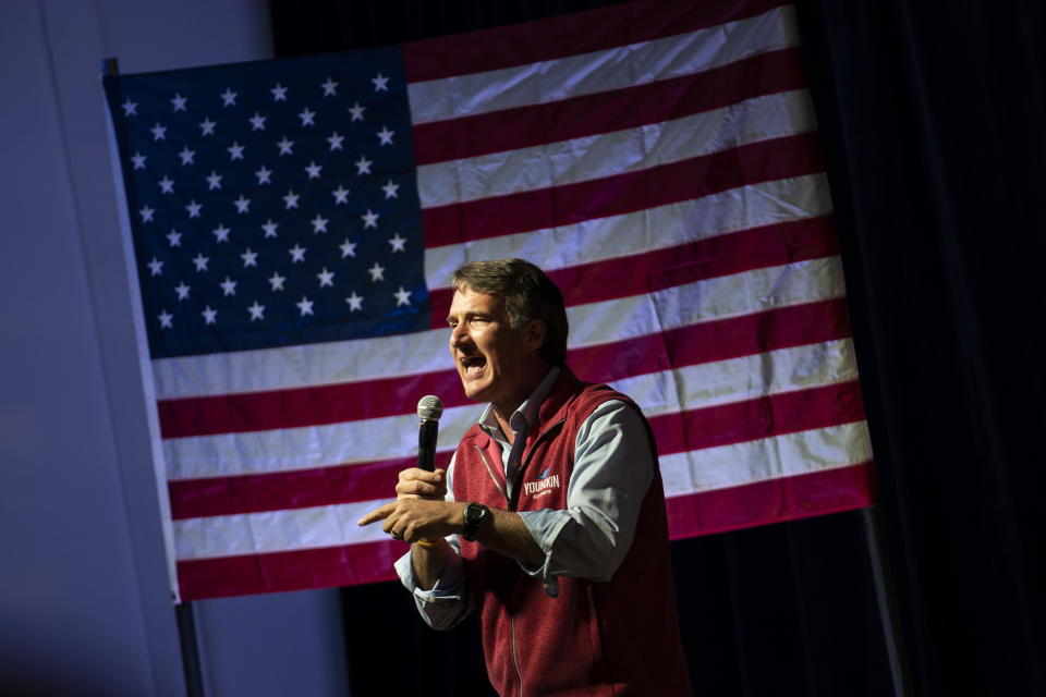 Gov. Glenn Youngkin takes the microphone in front of an American flag.