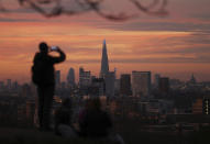 A person takes a photo of the skyline with the Shard building in the center, at sunset, from Greenwich Park in London, Tuesday, Nov. 24, 2020. (Yui Mok/PA via AP)