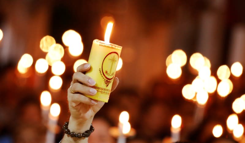 Catholic priest Anthony Dang Huu Nam holds a candle during a mass prayer for 39 people found dead in the back of a truck near London, UK at My Khanh parish in Nghe An province