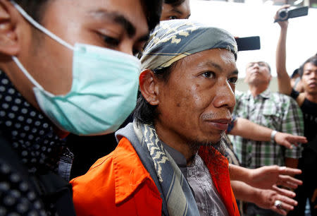 Plain clothes policemen guard Islamic cleric Aman Abdurrahman during his walk to the courtroom for his trial in Jakarta, Indonesia February 15, 2018. REUTERS/Beawiharta