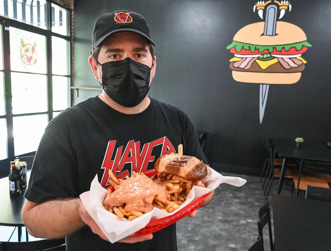 Jeremy Brownstein of Plant Slayer holds up a campfire burger with animal fries at the vegan restaurant’s location at The Galleria in downtown Fresno on Wednesday, Aug. 10, 2022.