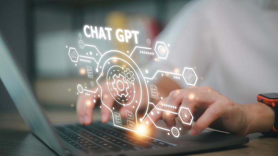 A digital graphic that says Chat GPT floats above a laptop computer.