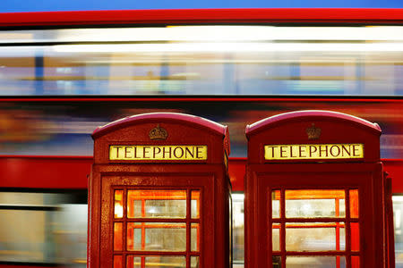 A bus passes traditional telephone boxes in London, Britain, November 3, 2013. REUTERS/Luke MacGregor/File Photo