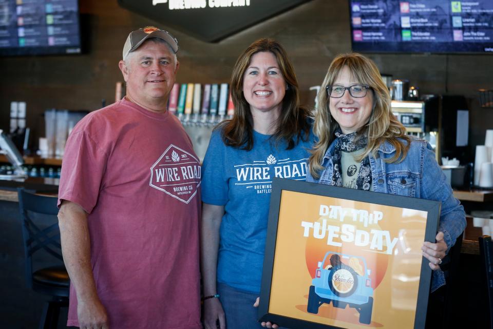 From left to right, Wire Road Brewing Company owner Kary Walker and Natalie Wlodarczyk and Shannon Stine of The Shandies pose for a portrait with the Day Trip Tuesday promotional art at Wire Road Brewing Company on Tuesday, May 2, 2023. The Shandies and Wire Road have partnered to release a collaborative non-alcoholic pale ale on May 16.