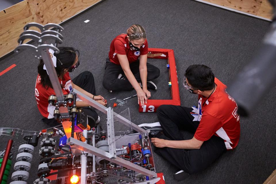 Gaby Hernandez (from left), Ashley Faucher and Pedro Rojo work to attach bumpers to Red Bull at Si Se Puede Foundation STEM Center in Chandler on April 13, 2022.