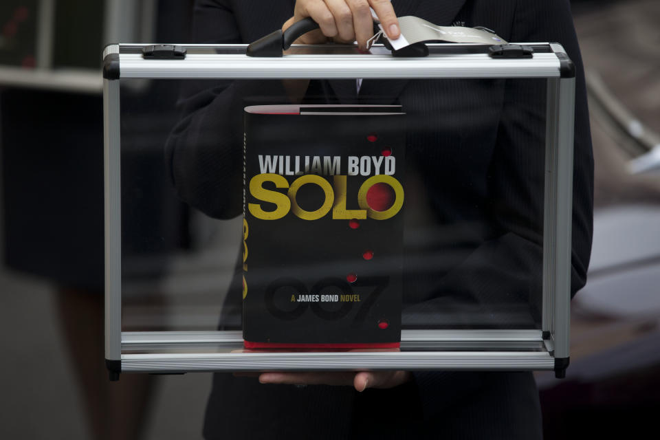 A flight attendant poses for photographers with a copy of the new James Bond novel "Solo" during a launch photocall outside the Dorchester Hotel in London, Wednesday, Sept. 25, 2013. "Solo" is set in 1969 and takes the suave British spy, 45 years old and feeling his age, from London's plush Dorchester Hotel to a war-torn West African country and to Washington. (AP Photo/Matt Dunham)