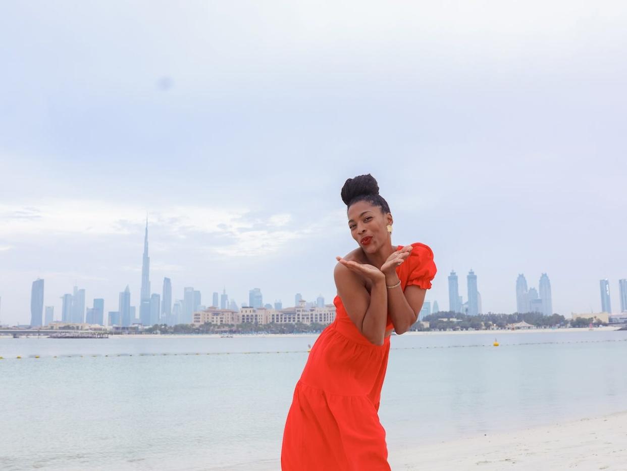 Monet Hambrick wearing a one-sleeved maxi dress on a beach in Dubai.