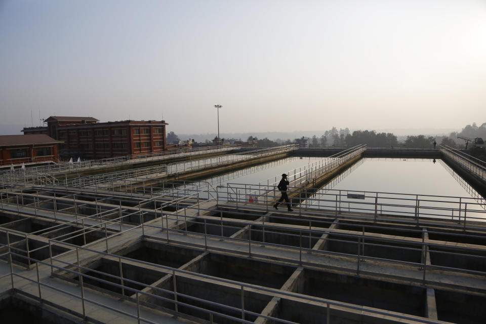 A Nepalese security guard walks at the construction site of Melamchi water project in Kathmandu, Nepal, Wednesday, Dec. 19, 2018. The government of Nepal has stopped Italian contractors from leaving the Himalayan country in an effort to complete a critical but much delayed water supply project for the capital city. The Italians have been working for the past four years but the Melamchi project is nearly two decades old and supposed to bring drinking water to Kathmandu, where households have water for only two hours every five days. (AP Photo/Niranjan Shrestha)