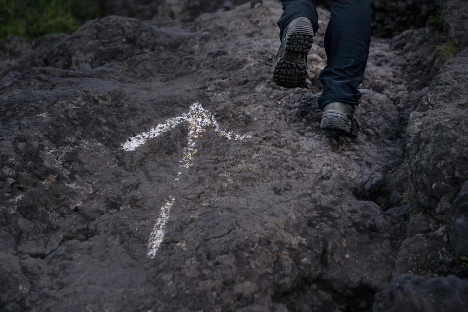 A climber makes his way along the Yoshida trail past an arrow sign as he heads to the summit of Mount Fuji, Friday, Aug. 2, 2019, in Japan. The Yoshida trail is the easiest and most popular among the climbing routes, with climbers wearing headlamps and carrying heavy packs spaced just feet apart on the rugged, rocky terrain. (AP Photo/Jae C. Hong)