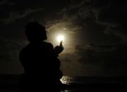 PALM COVE, AUSTRALIA - NOVEMBER 14: A spectator attempts to take a picture with his phone during the solar eclipse on November 14, 2012 in Palm Cove, Australia. Thousands of eclipse-watchers have gathered in part of North Queensland to enjoy the solar eclipse, the first in Australia in a decade. (Photo by Ian Hitchcock/Getty Images)