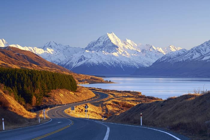 A winding road with mountains in the backdrop in New Zealand