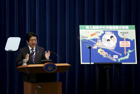 Japan's Prime Minister Shinzo Abe speaks next to a placard showing a defensive scenario for the protection of Japanese nationals overseas, during a news conference at his official residence in Tokyo in this July 1, 2014 file photo. REUTERS/Yuya Shino/Files